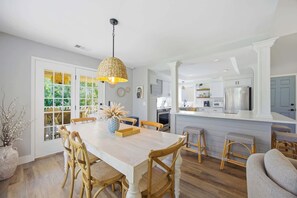 Una cocina amplia con armarios blancos, una isla central y un comedor con sillas de madera y una mesa.