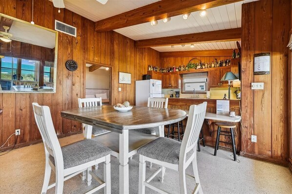 A wooden interior with a dining table, chairs, a kitchen area, and a bar.