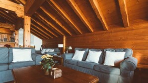 Una sala de estar acogedora con vigas de madera, un conjunto de sofás, una mesa de centro y una zona de bar con botellas.