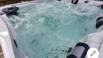A hot tub with a visible water pump and jets, surrounded by a wooden deck.