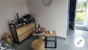 Une chambre moderne avec un meuble en bois, une petite table avec des boissons, un miroir rond et une vue sur l’extérieur.