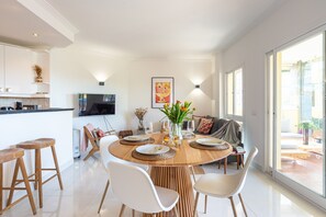 Une cuisine moderne avec un coin repas, un téléviseur et une grande fenêtre.