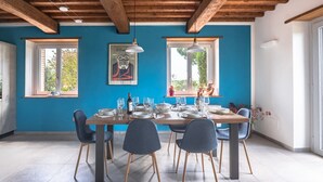 Un comedor con pared azul, vigas de madera en el techo y una mesa preparada para cuatro comensales.