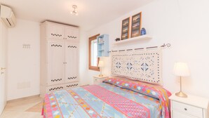 Camera da letto con un letto, armadio, comodino, lampada e pannello decorativo a parete.