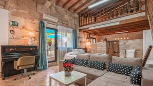 A rustic room with a piano, sofa, and a view of the outdoors. - Apartment "Segles 11" with Shared Pool & Wi-Fi (Campos)