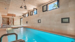 An indoor swimming pool with clear water, wooden ceiling, and multiple windows. - Apartment "Segles 11" with Shared Pool & Wi-Fi (Campos)