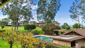 A pool area with a view of a building complex in the background. - Summer Deal Waikoloa 3BR Villa with Pool Hot Tub and Ocean Views (Waikoloa)