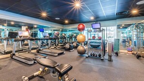 Une salle de sport équipée de tapis de course, de ballons d’exercice et d’appareils de musculation.