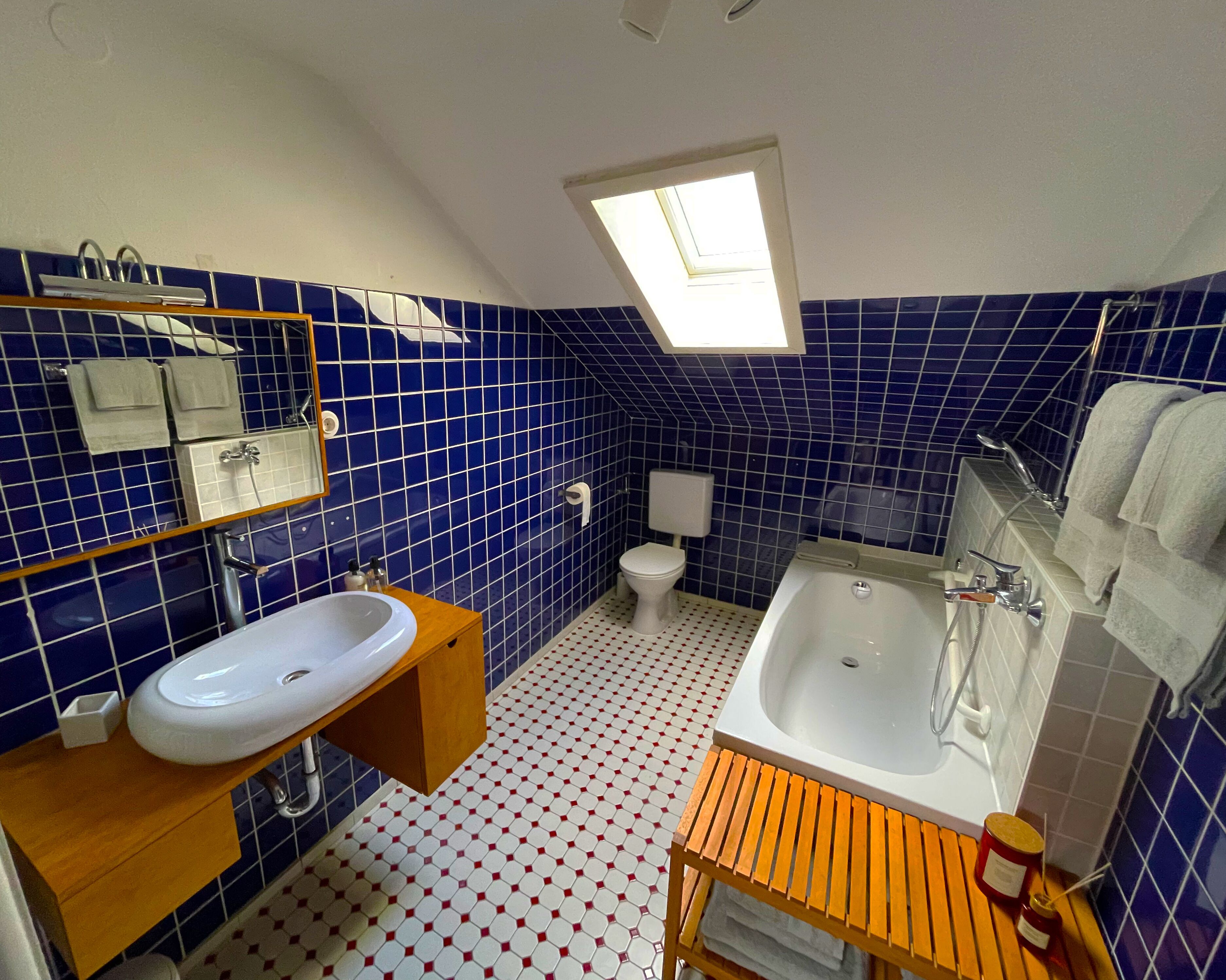 Une salle de bain avec un puits de lumière, un lavabo, des toilettes et une baignoire.