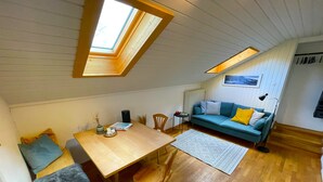 Un acogedor espacio tipo loft con suelo de madera, una mesa de comedor, un sofá y un tragaluz.