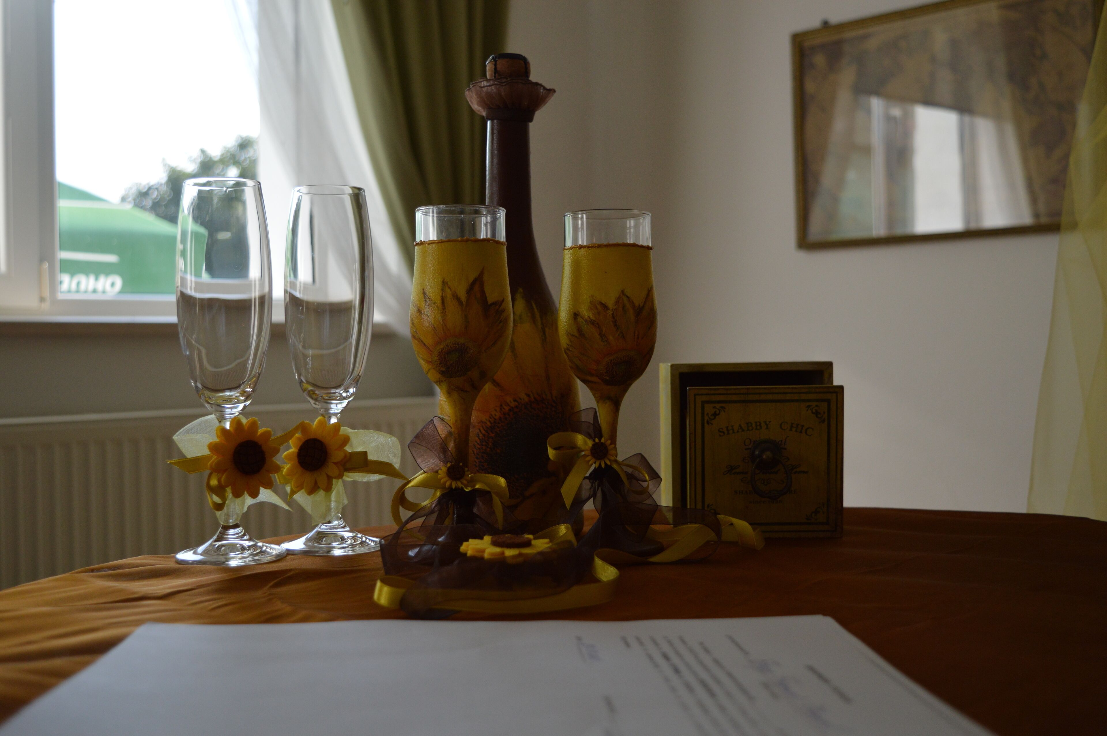 A table with three glasses of a yellow beverage, a decorative bottle, and a framed certificate.