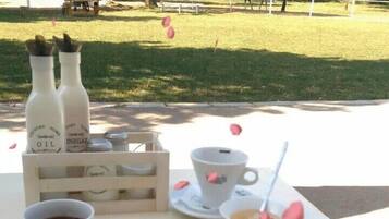 A picnic setup with food and drinks on a table, surrounded by a park.