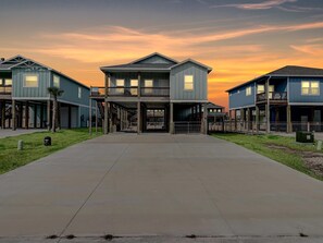 Une rangée de maisons de ville modernes à deux étages, avec un espace ouvert central et un ciel au coucher du soleil.