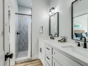 Une salle de bain moderne avec une douche, un grand miroir et un meuble-lavabo.
