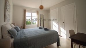 Una camera da letto con un letto grande, un comodino, una sedia, una finestra con tende e una porta.