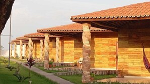 Una fila di edifici in legno con tetti in tegole e colonne in pietra, immersa in un prato curato e un vialetto lastricato.