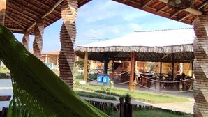 Un'area esterna riparata con un'amaca, pilastri in mattoni e una struttura con tetto di paglia.
