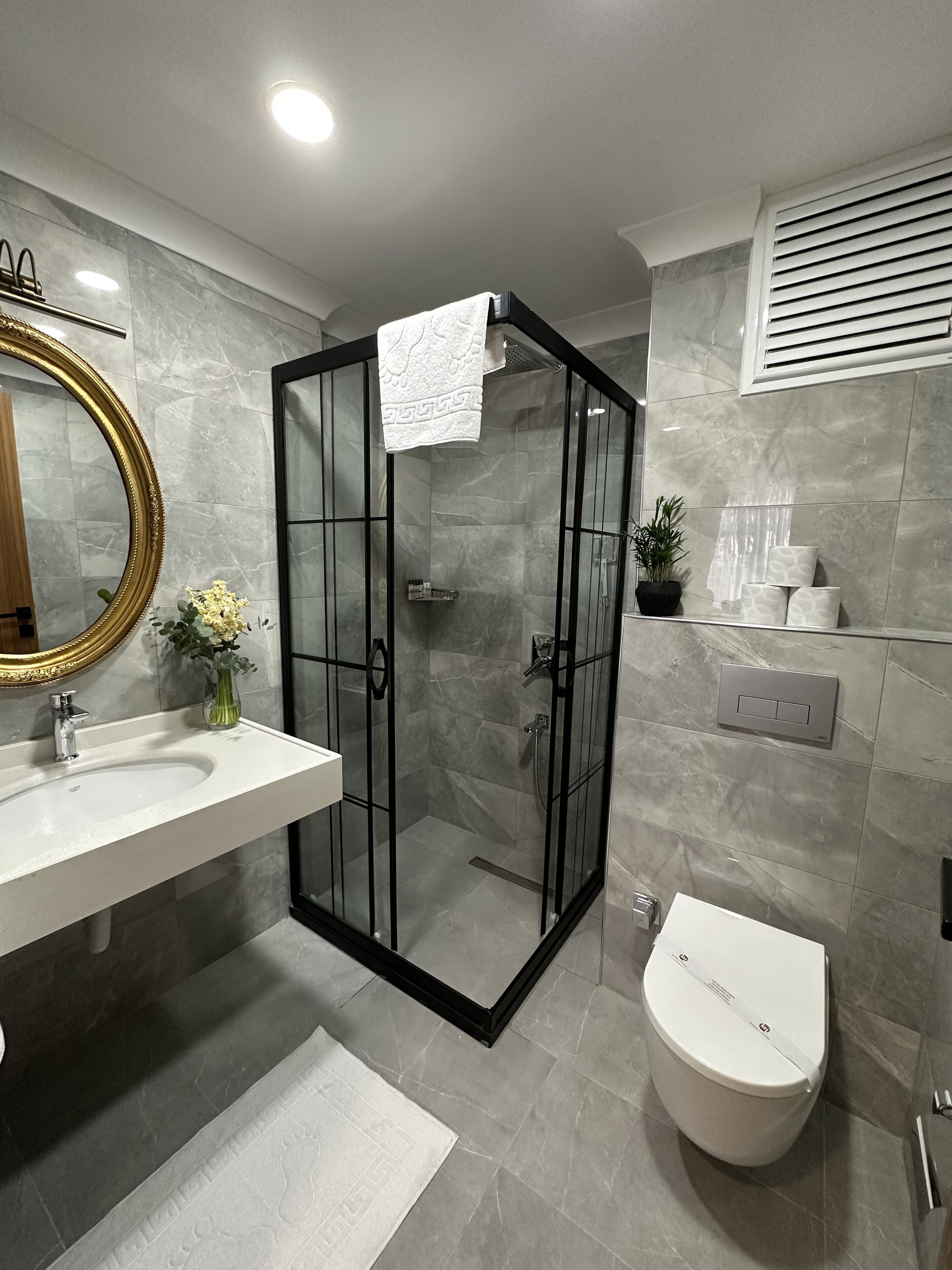 A modern bathroom with a glass-enclosed shower, a white sink, and a toilet.