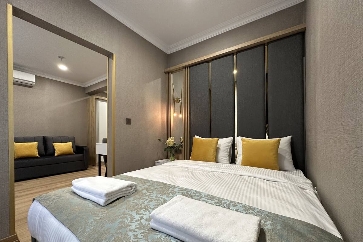 Una camera d'albergo moderna con un letto grande, un divano e uno specchio.