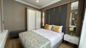 A modern hotel room with a large bed, a bedside table, a mirror, and a wardrobe.