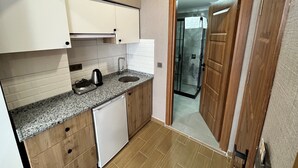 A compact kitchen with a built-in dishwasher, a sink, and a coffee maker. - H&L Suites (Istanbul)
