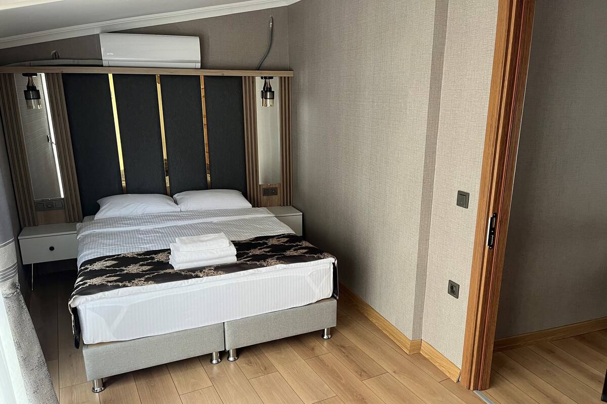 Camera d'albergo moderna con un letto grande, comodini e condizionatore d'aria integrato.