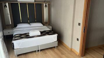 A modern hotel room with a large bed, bedside tables, and a built-in air conditioning unit.