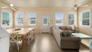 A room with a dining table, chairs, a sofa, and a ceiling fan. - Pool, Near Beach & 4BR Family Home - Just Wanna Have Sun (Port Aransas)