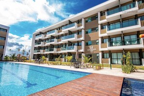 A modern hotel with a pool, multiple balconies, and a sign reading "OHANA".