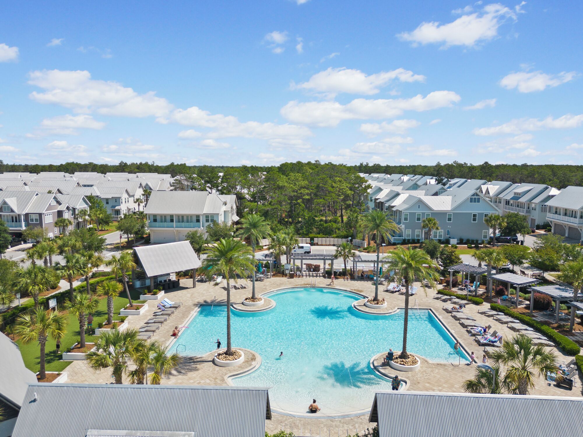 Un resort con piscina central rodeada de palmeras y sillas de descanso.
