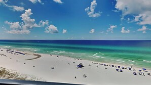 Una playa con agua turquesa cristalina, arena blanca y algunas sombrillas.
