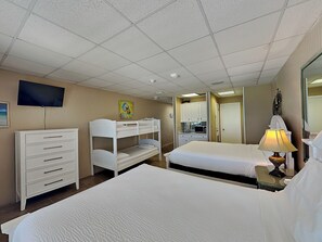 A hotel room with bunk beds, a desk, a television, a microwave, and a lamp.