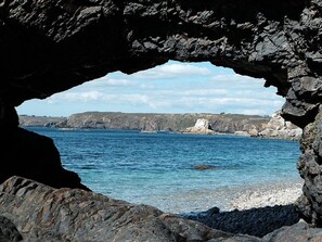 A coastal scene with a rocky shoreline and a clear blue sea.