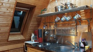 Cocina compacta con encimera negra, electrodomésticos de acero inoxidable y paredes de madera.