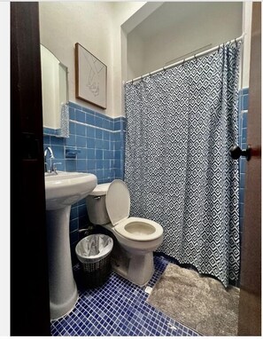 Un baño con inodoro, lavabo y suelo de azulejos azules.