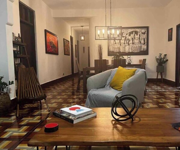 A living room with a sofa, a coffee table, and a patterned floor. There is a painting on the wall and a chandelier. - Cozy, Classic & Gorgeous Apt near Condado beach 5 bedrooms 3 bathrooms 1Parking (San Juan)