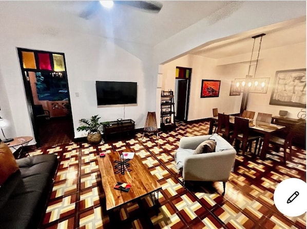 Una sala de estar con piso estampado, un sofá, una mesa de centro y un televisor montado en la pared.