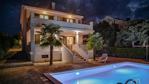 Una casa moderna de dos pisos con piscina, escaleras y una silla de descanso.