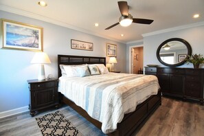 A bedroom with a bed, nightstands, a ceiling fan, and wall art. - Wake up to picturesque views of the ocean, beach and boardwalk (Virginia Beach)