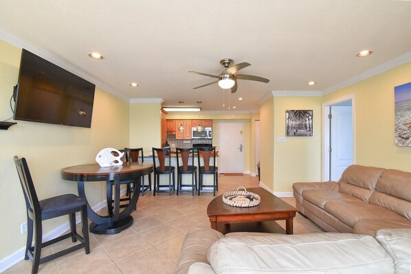 A living room with a sofa, a coffee table, and a dining area with chairs and a table.