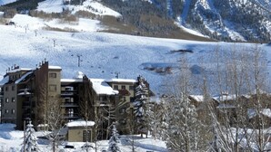 A mountain resort with snow-covered slopes, a ski lift, and buildings with balconies. - Easy Access to Skiing!  Elevator, Hot Tub! (Mount Crested Butte)