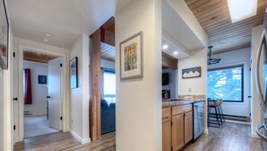 A modern kitchen with wooden cabinets, a dining area with bar stools, and a large window providing natural light. - Easy Access to Skiing!  Elevator, Hot Tub! (Mount Crested Butte)