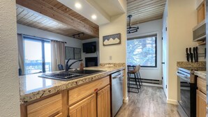 A modern kitchen with wooden cabinets, a granite countertop, and a built-in dishwasher. - Easy Access to Skiing!  Elevator, Hot Tub! (Mount Crested Butte)