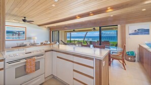 A modern kitchen with a large island, wooden ceiling, and a view of the ocean. - Spectacular Oceanfront 4 bedroom 4 bath, AC, pool in tropical oasis. (Lahaina)
