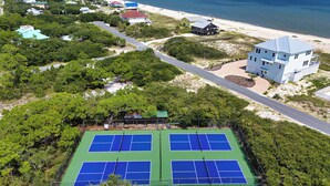An aerial view of a coastal area with a tennis court, beach, and residential buildings. - Community Pool! Easy Beach Access! (St. George Island)
