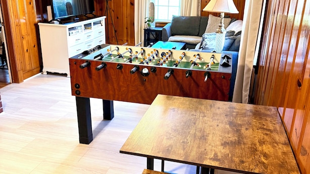 A room with a foosball table, a television, a sofa, and a dining table. - 3 bedroom cozy yet spacious home w/ in-ground pool (Richmond)