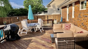 A wooden deck with outdoor furniture, including a table and chairs, and a wicker sofa. - 3 bedroom cozy yet spacious home w/ in-ground pool (Richmond)