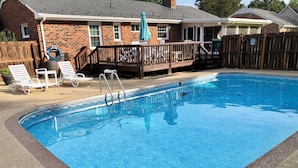 A swimming pool with a wooden deck, lounge chairs, and a hose reel. - 3 bedroom cozy yet spacious home w/ in-ground pool (Richmond)