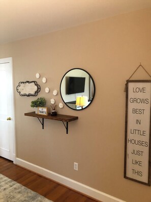 A wall with a mirror, a shelf with decorative items, and a motivational quote. - 3 bedroom cozy yet spacious home w/ in-ground pool (Richmond)