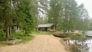 Un sentier sablonneux menant à un chalet au bord d’un lac, entouré d’arbres.